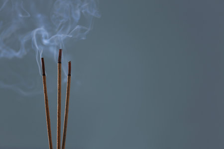 Incense sticks smoldering on blurred background, closeup. Space for textの写真素材