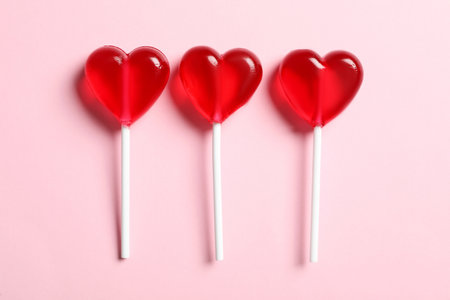 Sweet heart shaped lollipops on pink background, flat lay. Valentine's day celebrationの写真素材