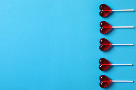 Sweet heart shaped lollipops on light blue background, flat lay with space for text. Valentine's day celebrationの写真素材