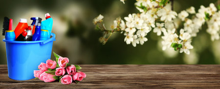 Various cleaning supplies and spring flowers on wooden table outdoors, space for text. banner designの写真素材