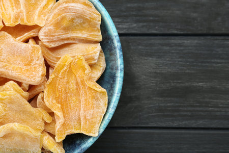 Delicious dried jackfruit slices in bowl on black wooden table, top view. Space for textの写真素材