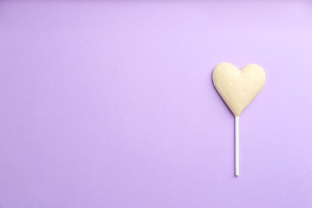 Chocolate heart shaped lollipop on light lilac background, top view. Space for textの写真素材