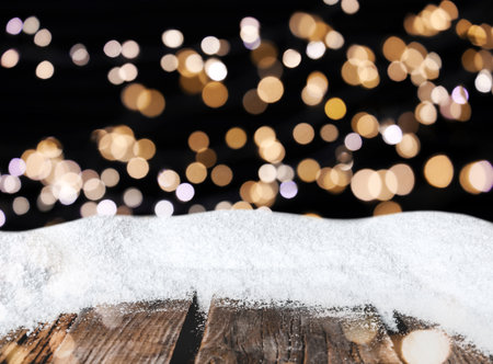 Wooden surface with heap of snow and blurred Christmas lights on background, bokeh effectの写真素材