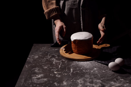 Young woman making traditional Easter cake at table against black background, closeup. Space for textの写真素材