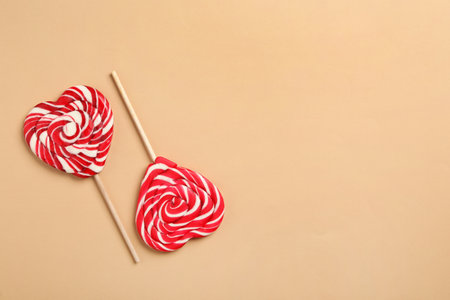 Sweet heart shaped lollipops on beige background, flat lay with space for text. Valentine's day celebrationの写真素材