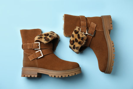 Stylish brown boots on light blue background, top view