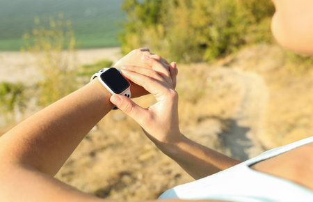 Woman checking modern smart watch during training outdoors, closeupの写真素材