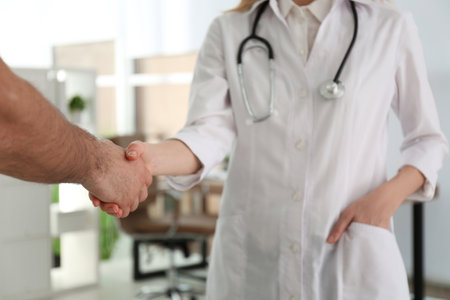 Doctor and patient shaking hands in clinic, closeupの写真素材