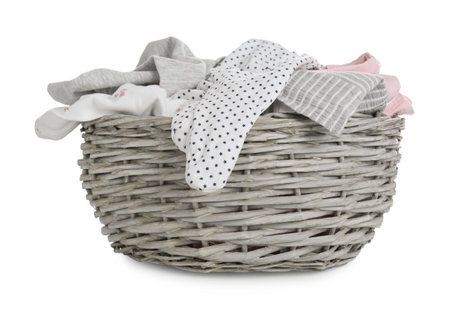 Wicker basket with baby clothes isolated on whiteの写真素材