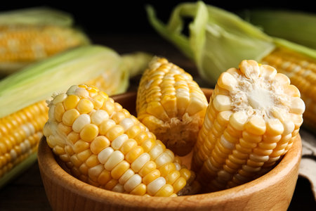 Tasty sweet corn cobs in bowl on table, closeup view