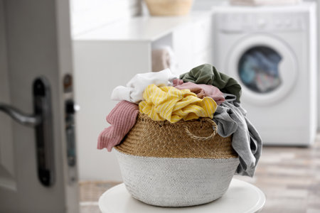 Wicker basket with dirty laundry on table indoorsの写真素材