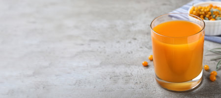 Delicious sea buckthorn juice on gray table, space for text. banner designの写真素材
