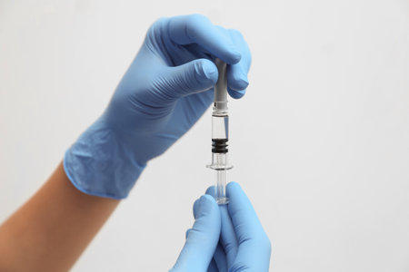 Doctor holding syringe with vaccine on light background, closeupの写真素材
