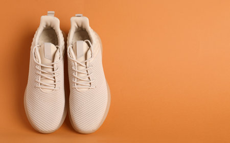 Pair of stylish sport shoes on orange background, top view. Space for textの写真素材