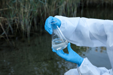 Scientist with conical flask taking sample from river for analysis, closeupの写真素材