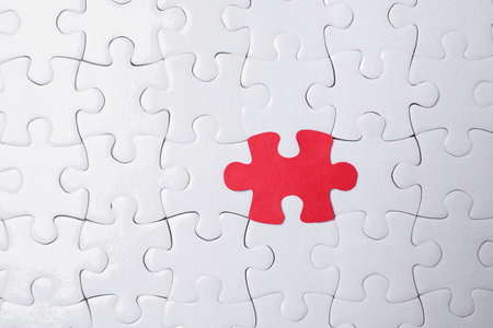 White jigsaw puzzles and red one as background, top viewの写真素材