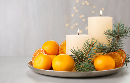Fresh tangerines, burning candles and fir tree branches on gray table, space for textの写真素材