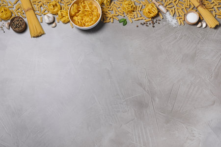 Flat lay composition with different types of pasta on gray table, space or textの写真素材