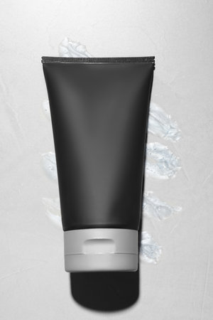 Black tube with men's cosmetic product on gray background, top viewの写真素材