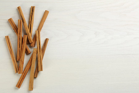 Aromatic cinnamon sticks on white wooden table, flat lay. Space for textの写真素材