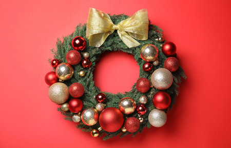 Beautiful Christmas wreath with festive decor on red backgroundの写真素材