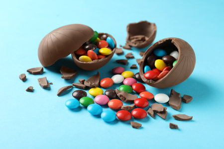 Broken chocolate eggs with candies on light blue backgroundの写真素材