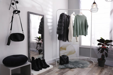 Stylish warm clothes on rack in dressing room interiorの写真素材