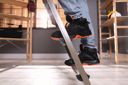 Person climbing ladder indoors, closeup on feet