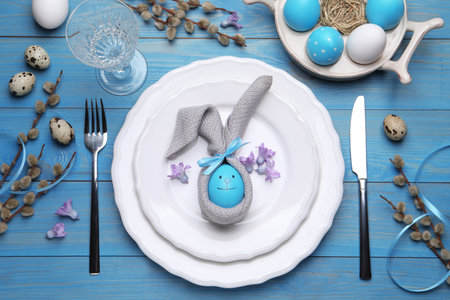 Festive Easter table setting with eggs on blue wooden background, flat lay