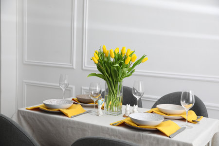 Beautiful Easter table setting with yellow tulips indoorsの写真素材