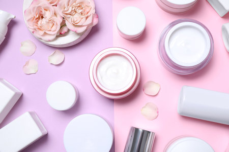 Flat lay composition with different skin care products and flowers on color backgroundの写真素材
