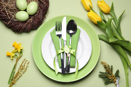 Festive Easter table setting with eggs on light green background, flat layの写真素材