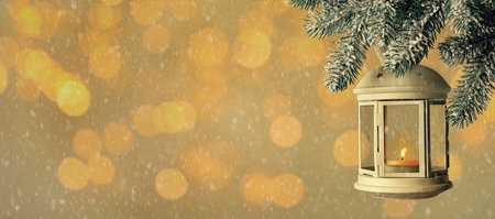 Vintage Christmas lantern with burning candle hanging on fir branch against color background, bokeh effect. Space for textの写真素材