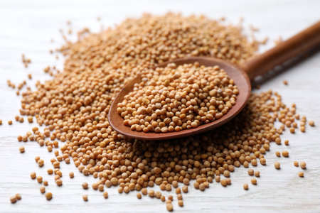 Mustard seeds with wooden spoon on white table, closeupの写真素材