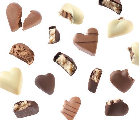 Delicious heart shaped chocolate candies falling on white backgroundの写真素材