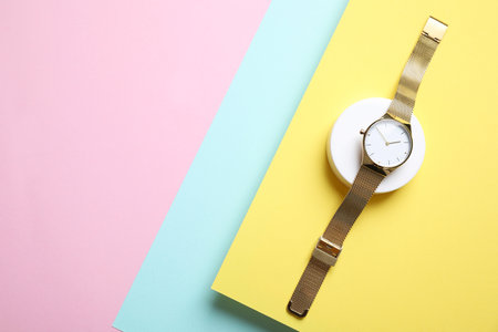 Stylish golden wristwatch on color background, top view. Space for textの写真素材