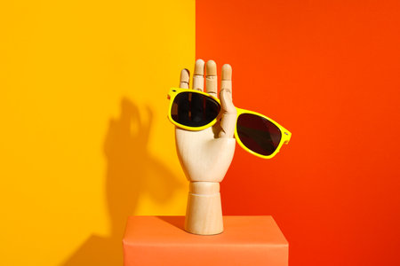 Wooden mannequin hand with stylish sunglasses on color backgroundの写真素材