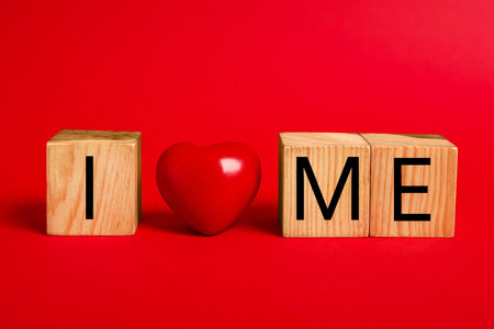 Phrase I Love Me made with wooden cubes and heart on red backgroundの写真素材