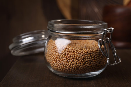 Mustard seeds in glass jar on wooden table, closeupの写真素材