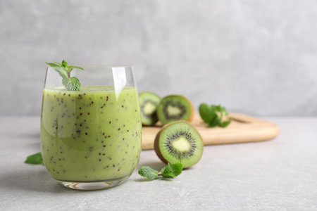 Delicious kiwi smoothie and fresh ingredients on light gray table, space for textの写真素材