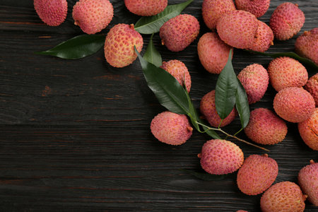 Fresh ripe lychee fruits on dark wooden table, flat lay. Space for textの写真素材