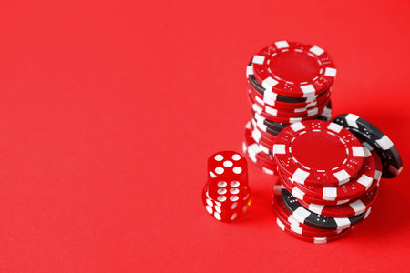 Poker chips and dice on red background, space for textの写真素材