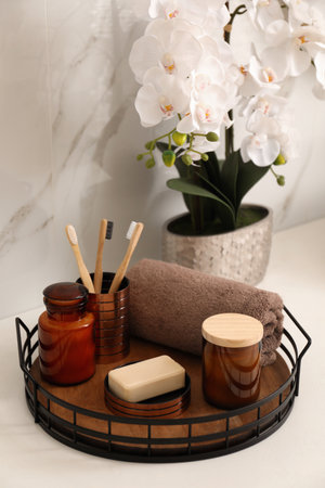 Beautiful flowers and different toiletries on countertop in bathroom