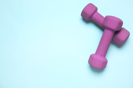 Bright dumbbells on light blue background, flat lay. Space for textの写真素材