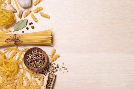 Flat lay composition with different types of pasta on light wooden table, space or textの写真素材