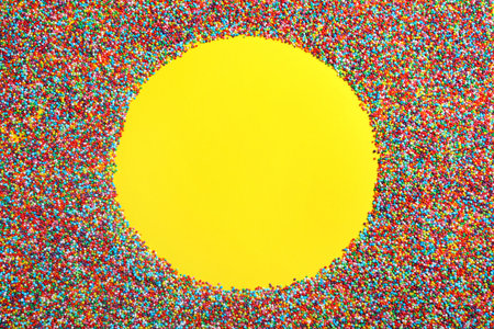 Frame of bright colorful sprinkles on yellow background, flat lay with space for text. Confectionery decorの写真素材