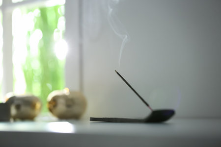 Incense stick smoldering on table in room. Space for textの写真素材