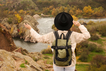 Traveler with backpack enjoying beautiful view near mountain river. autumn vacationの写真素材