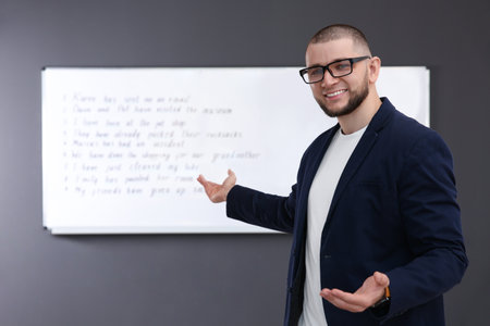 English teacher near whiteboard with task at lessonの写真素材