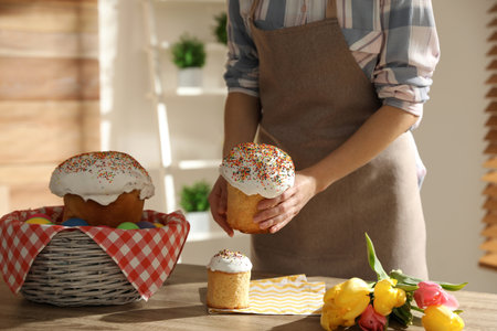 Woman traditional Easter cakes in basket putting indoors, closeup